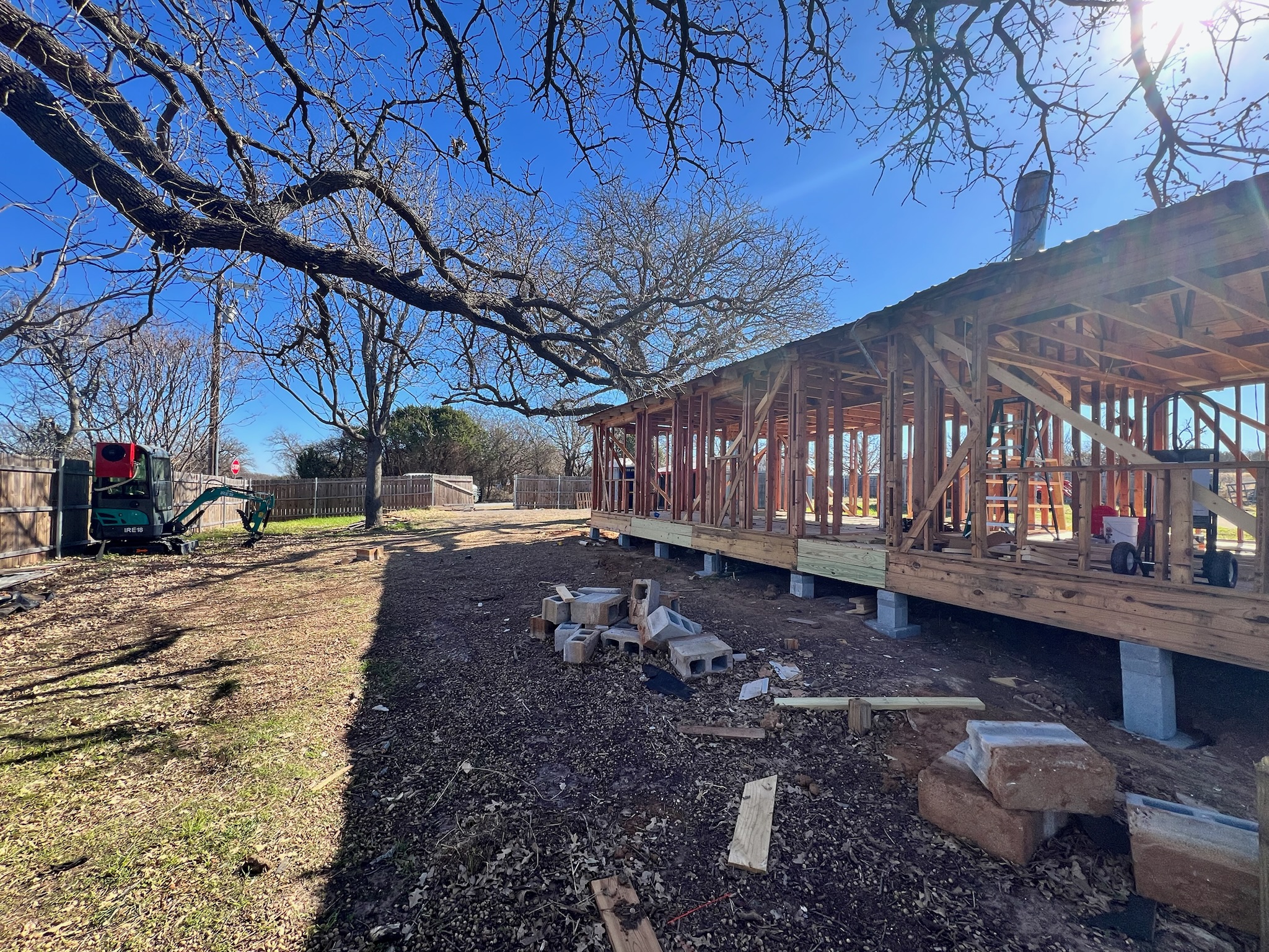A wide view of a framed-out shell with a small green Yanmar tractor in the frame.